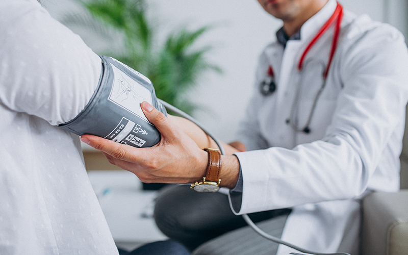 Young male psysician with patient measuring blood pressure